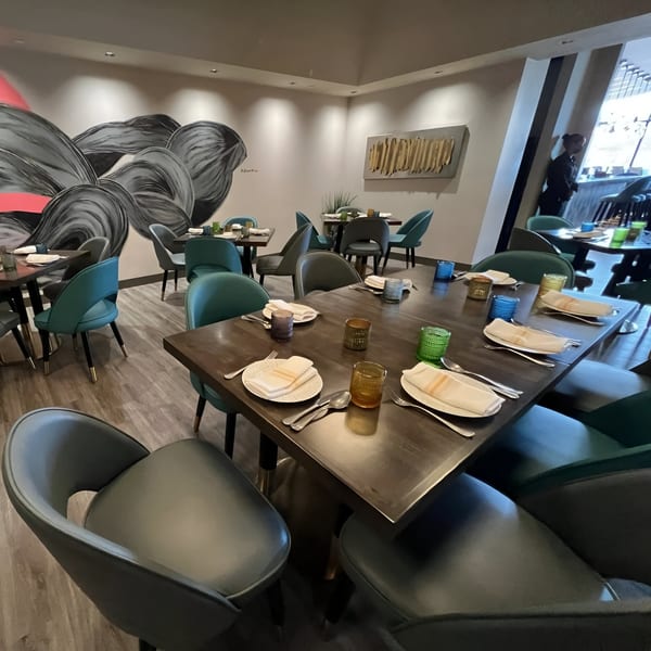 Tashan restaurant dining room with modern decor, set tables, and a large abstract mural.